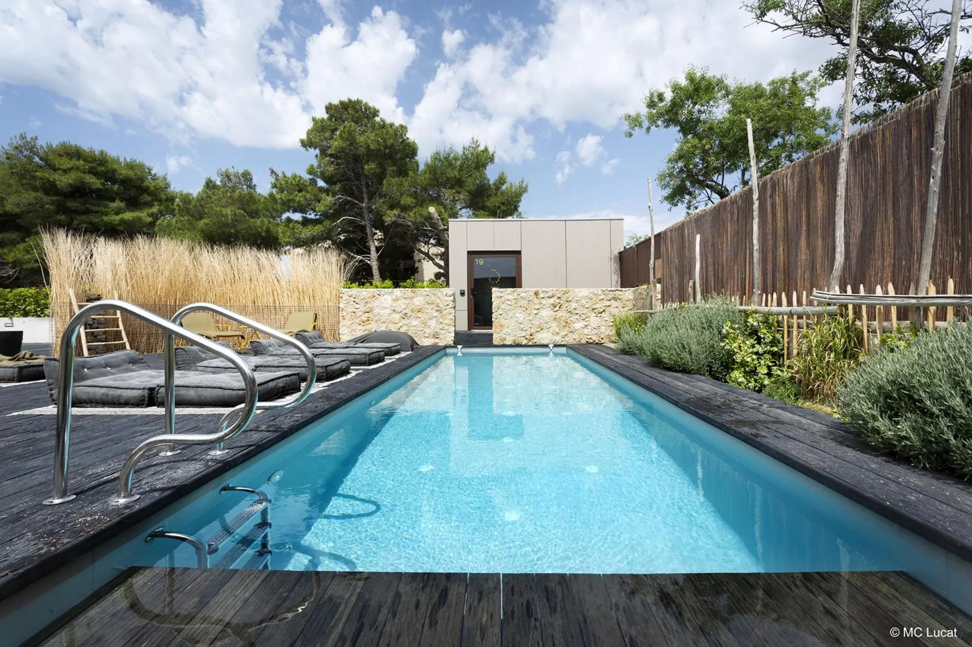 Une piscine rectangulaire bordée d'une terrasse en bois avec des chaises longues.
