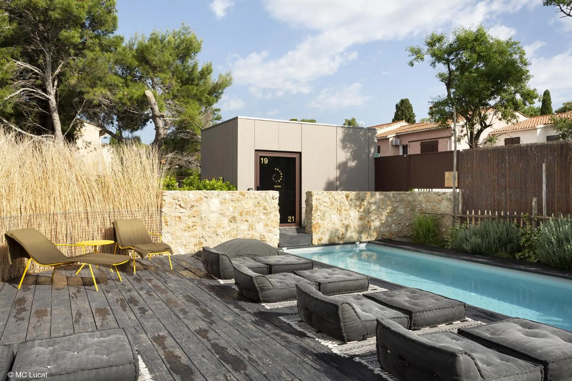 Terrasse en bois avec chaises longues et petite piscine rectangulaire.