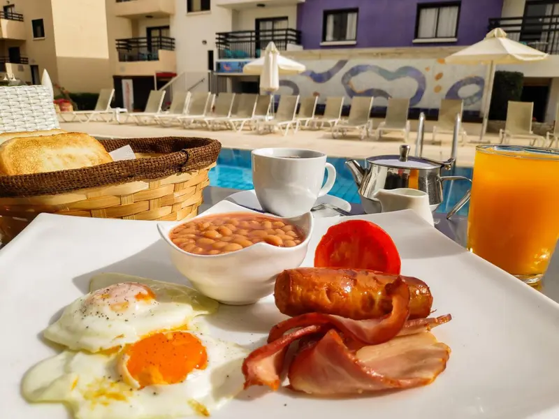 Un petit-déjeuner copieux est servi au bord d'une piscine ensoleillée.