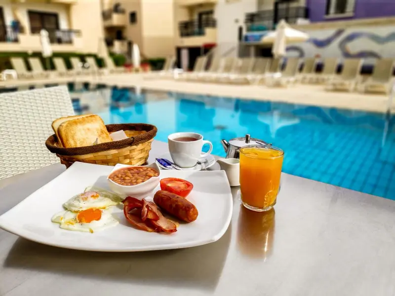 Un petit-déjeuner copieux est servi sur une table près d'une piscine.