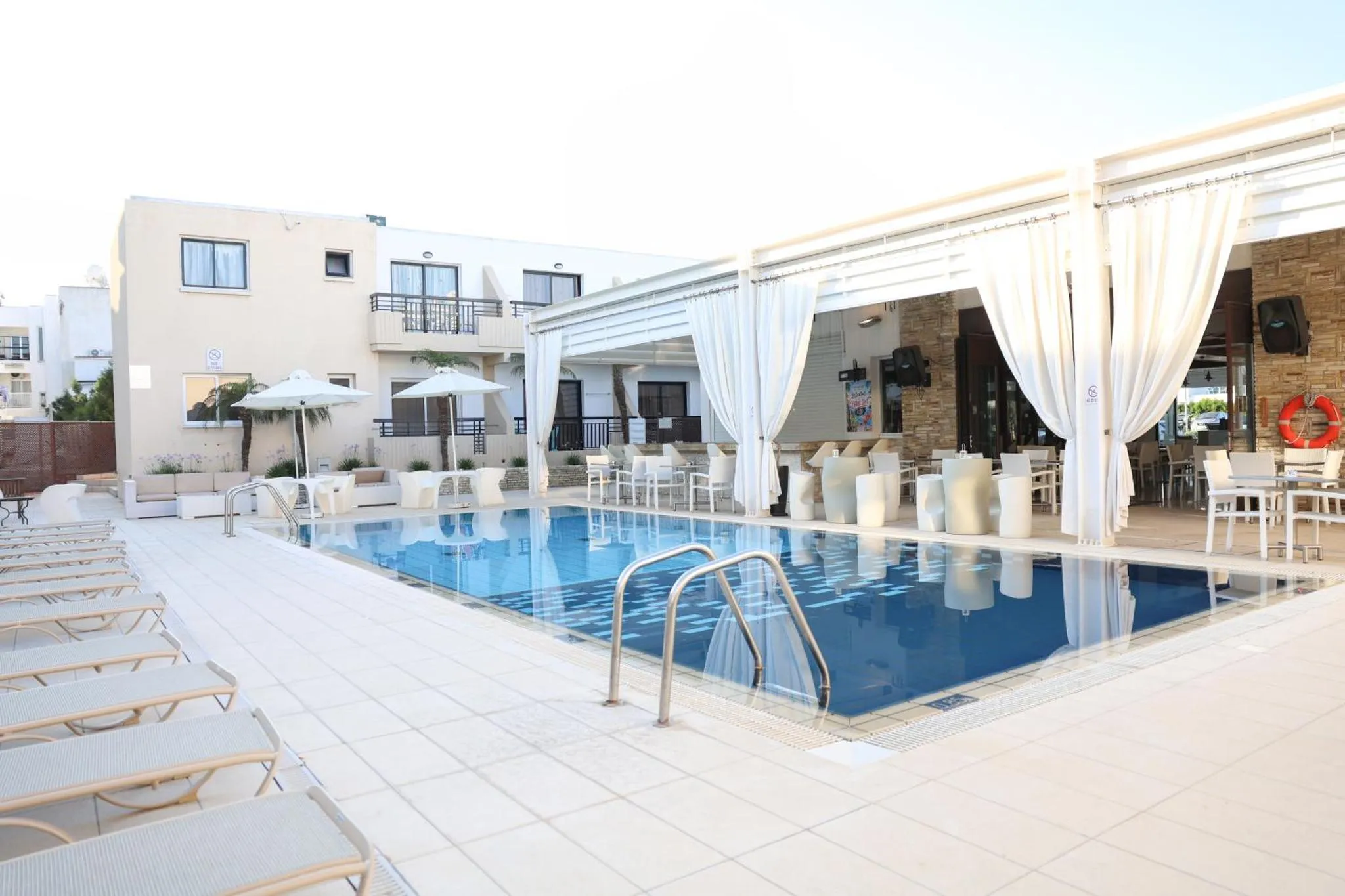 Terrasse avec piscine et mobilier de détente.