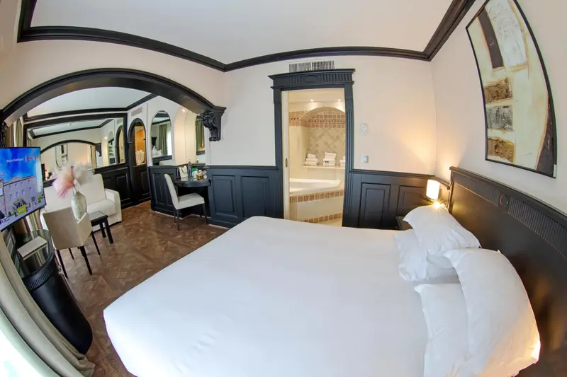 Chambre lumineuse avec un grand lit et un coin bureau.
