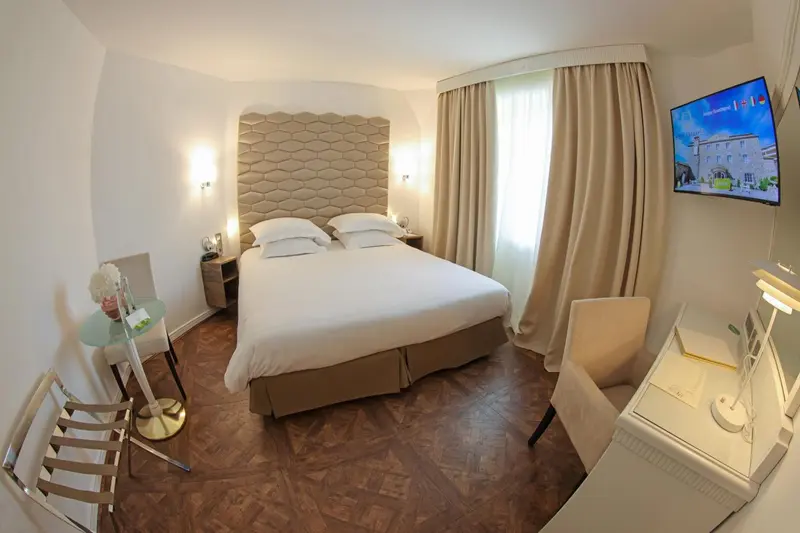 Une chambre lumineuse avec un grand lit et un téléviseur mural.
