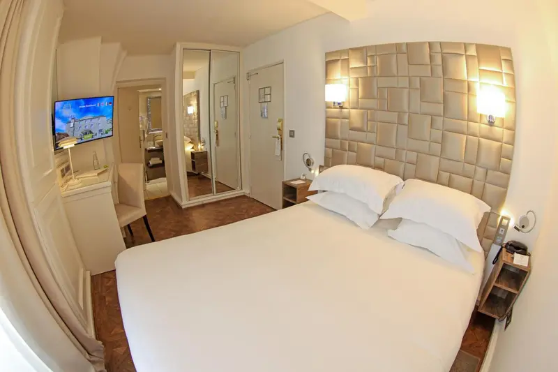 Une chambre lumineuse avec un grand lit et un téléviseur mural.