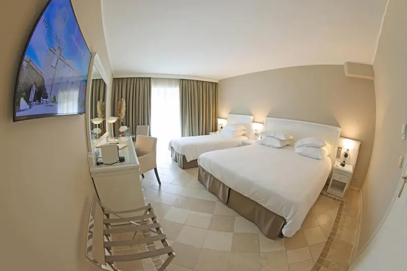 Chambre lumineuse avec deux lits et vue sur l'extérieur.