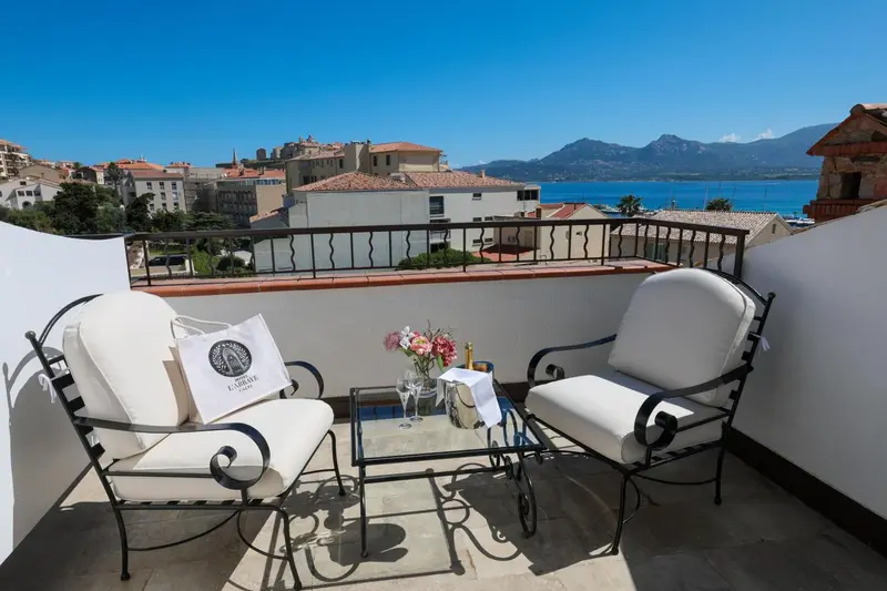 Terrasse avec mobilier d'extérieur et vue sur la ville et la mer.