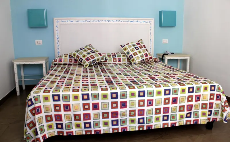 Une chambre lumineuse avec un grand lit recouvert d'une courtepointe colorée.