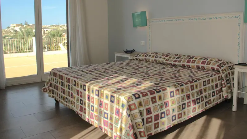 Une chambre lumineuse avec un grand lit recouvert d'une courtepointe colorée.