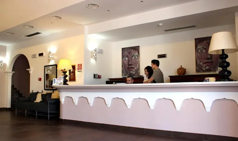 Un comptoir d'accueil lumineux avec du personnel et des canapés en arrière-plan.