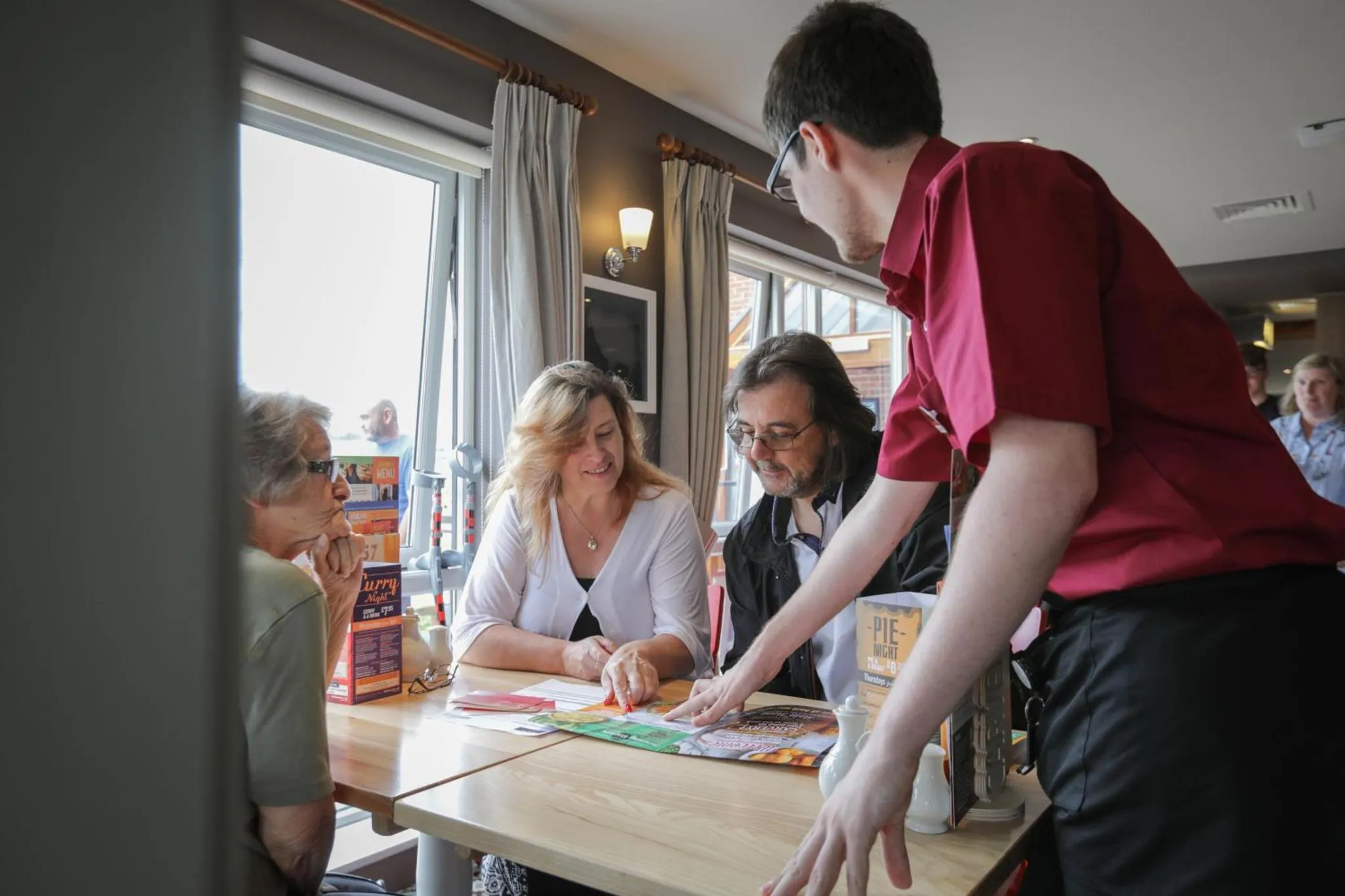 Des clients discutent avec un employé dans une salle lumineuse.