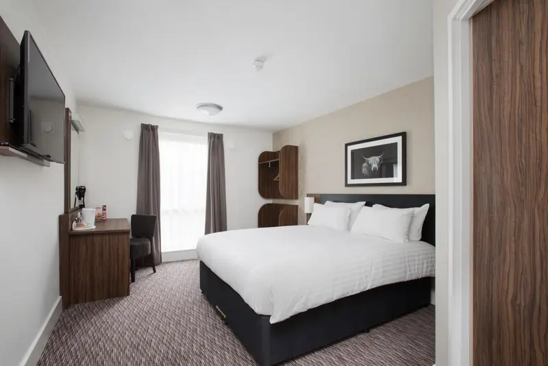 Une chambre d'hôtel lumineuse avec un grand lit et un bureau.