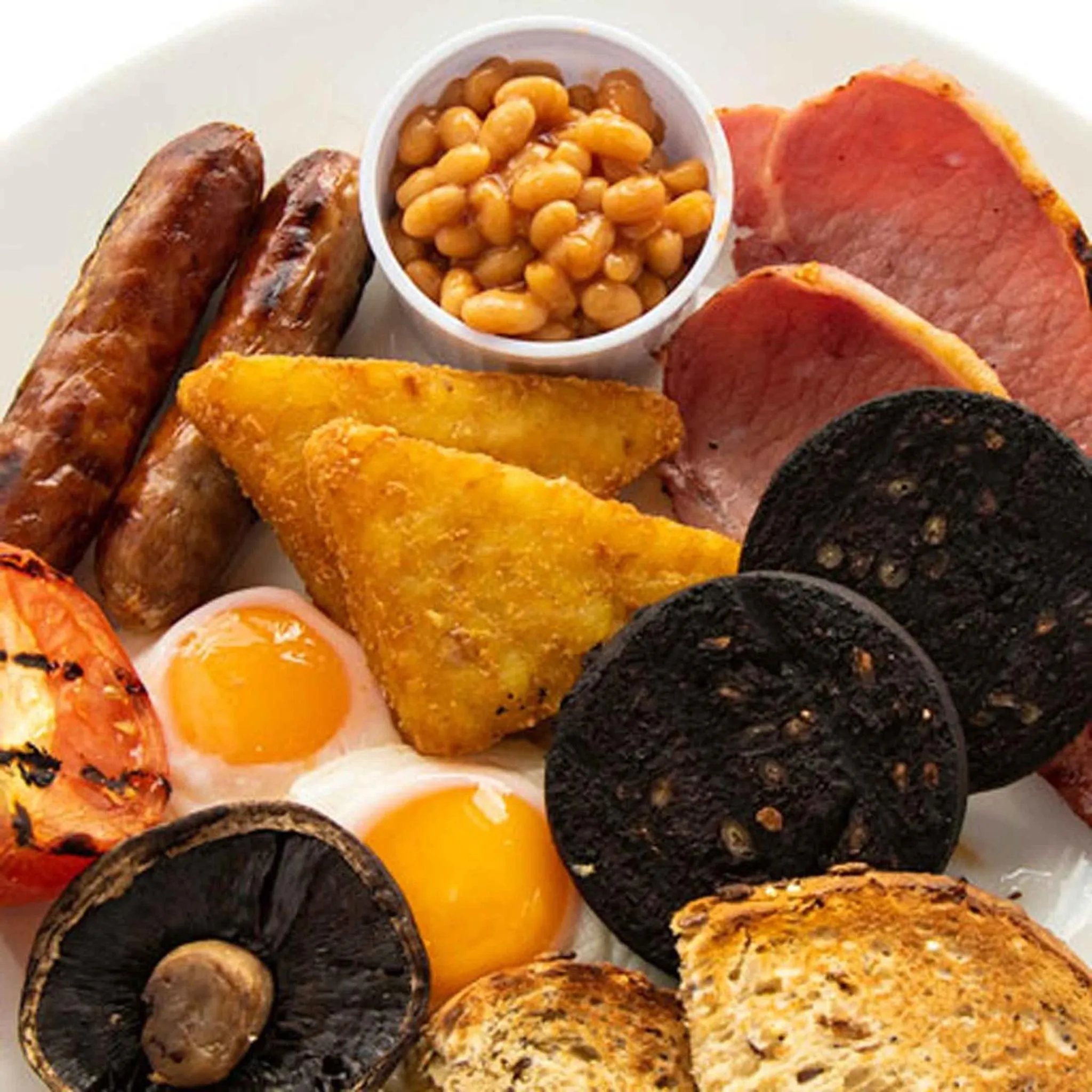 Assiette copieuse avec œufs, saucisses, bacon, haricots, champignons et pommes de terre.