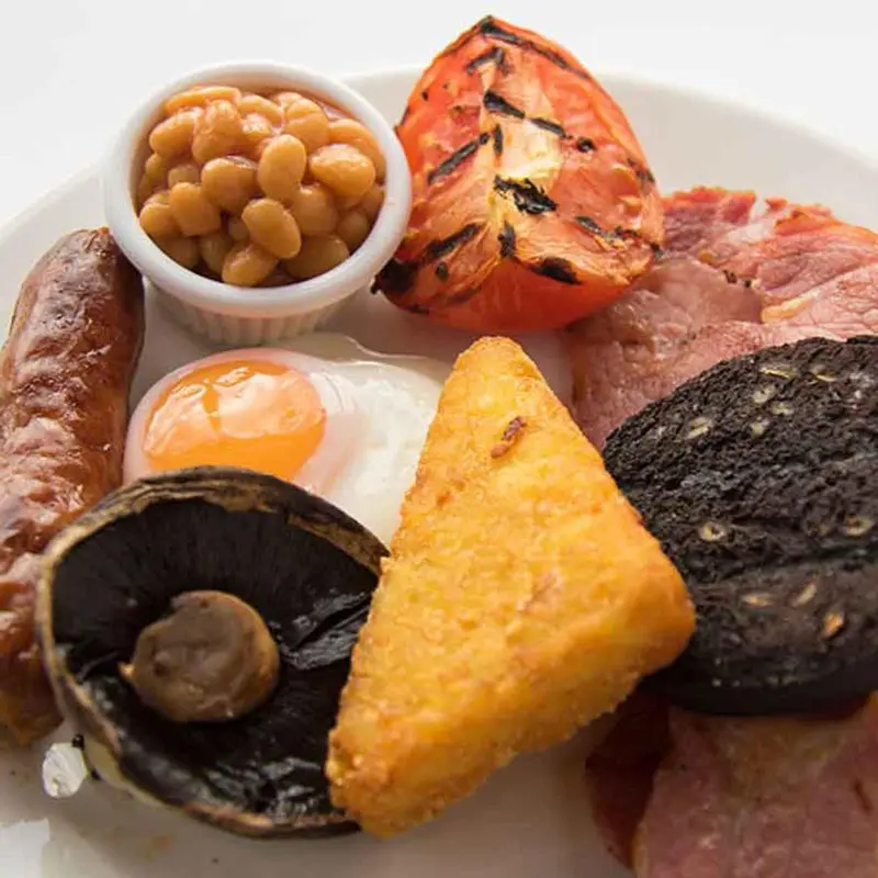Petit déjeuner anglais copieux avec œufs, haricots, tomates grillées et saucisses.