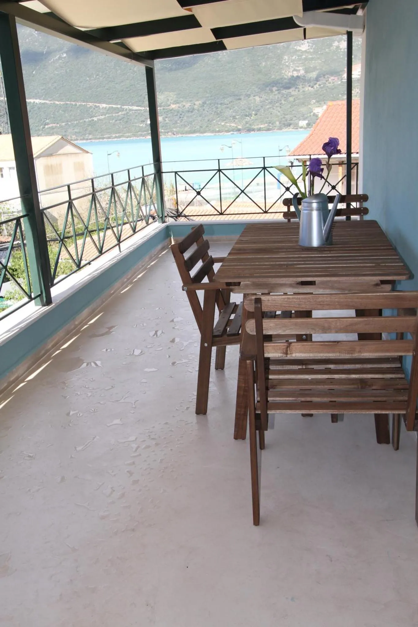 Une table et des chaises en bois sont disposées sur une terrasse avec vue sur la mer.