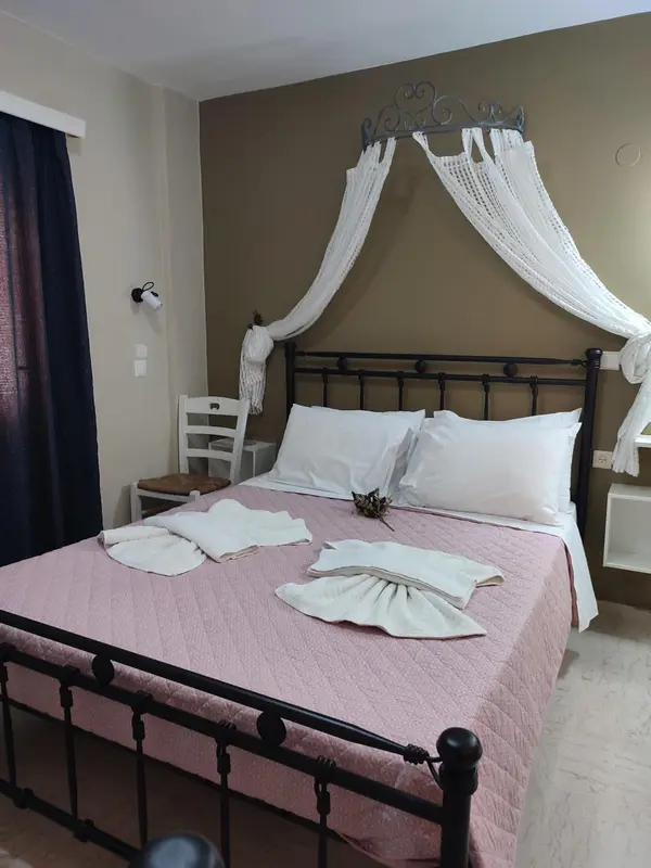 Un lit recouvert d'une courtepointe rose et de draps blancs est orné de serviettes pliées.