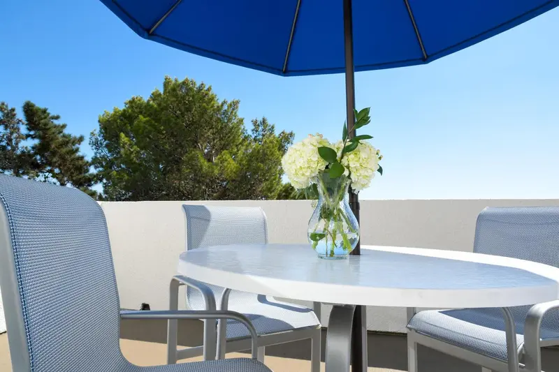 Une table ronde et des chaises sur une terrasse ensoleillée.
