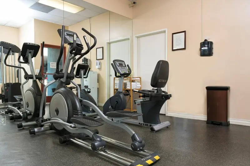 Une salle de sport avec plusieurs appareils de musculation et des miroirs.