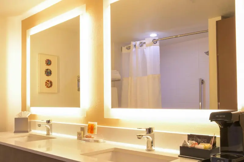 Salle de bain lumineuse avec deux vasques et un grand miroir.