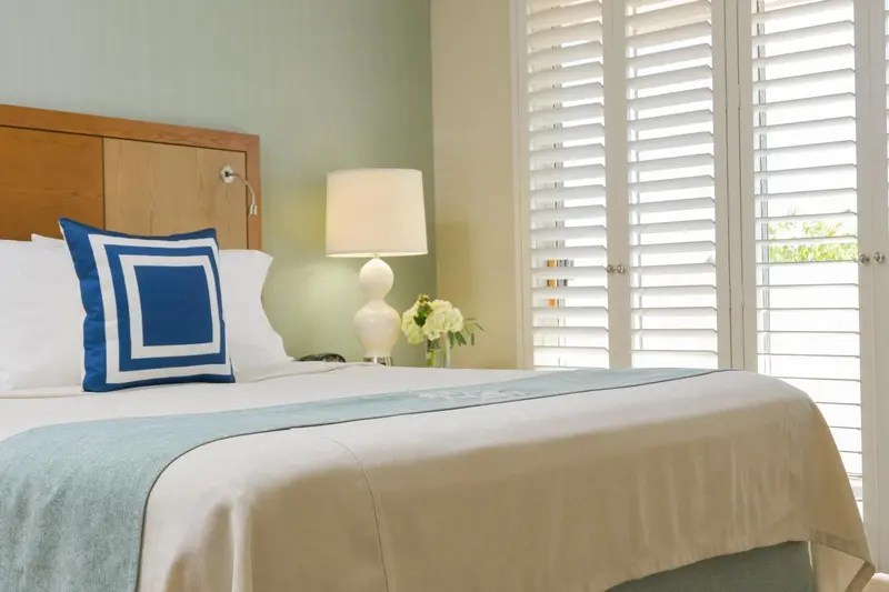 Un lit avec oreillers bleus et une couverture claire dans une chambre lumineuse.