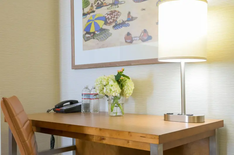 Une table en bois avec une lampe et un bouquet de fleurs dans une pièce lumineuse.