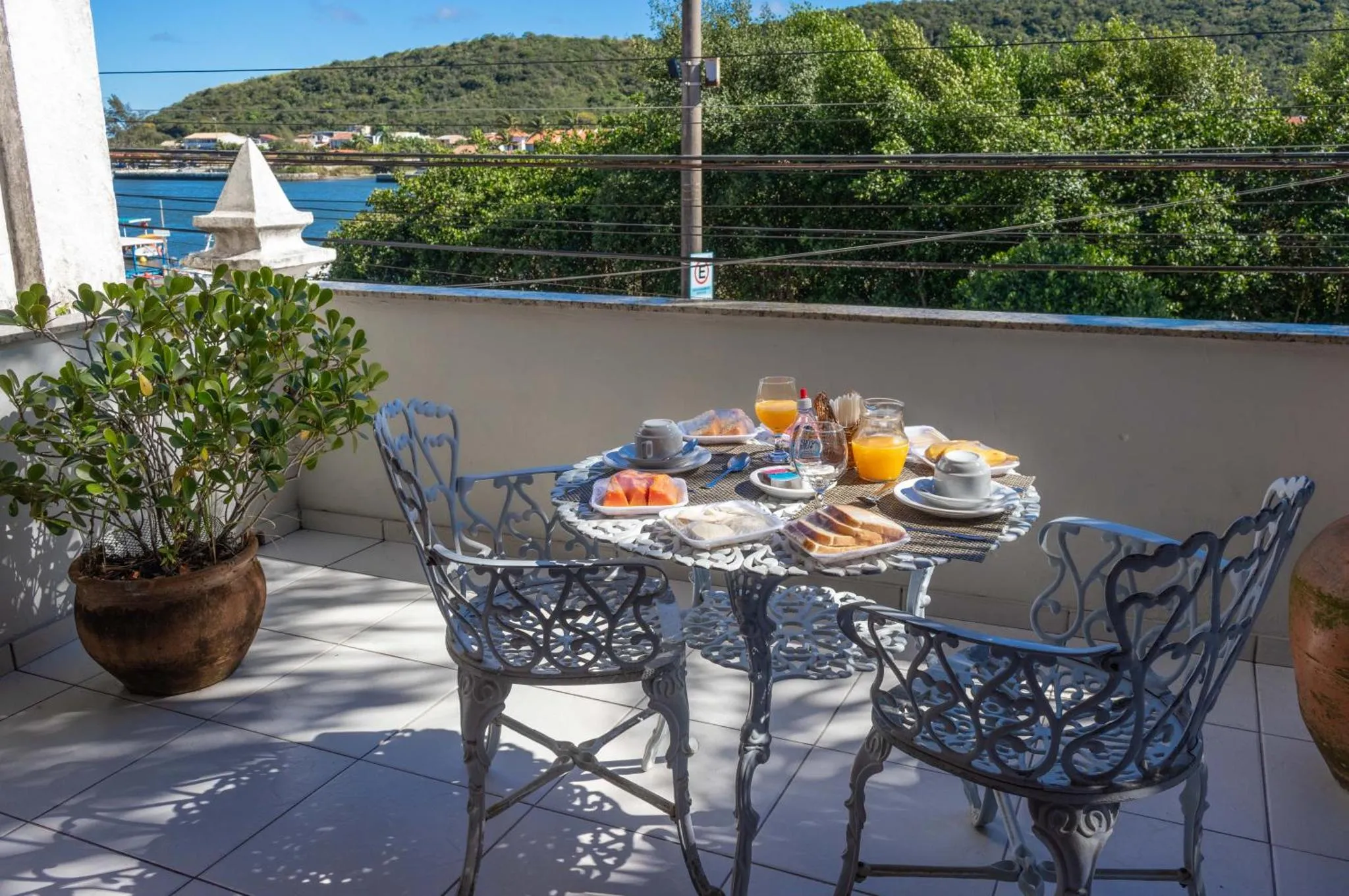 Une table de petit-déjeuner est dressée sur une terrasse ensoleillée avec vue sur la mer.