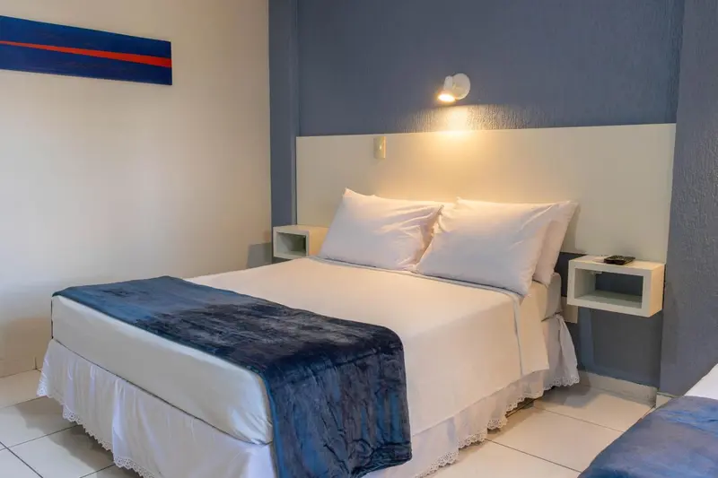 Une chambre lumineuse avec un grand lit recouvert d'une courtepointe blanche et bleue.