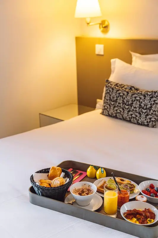 Un petit-déjeuner est servi sur un plateau posé sur un lit dans une chambre.