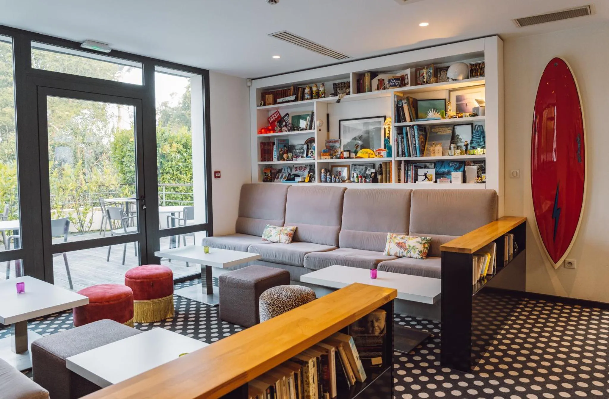 Espace de détente lumineux avec canapés et bibliothèque.
