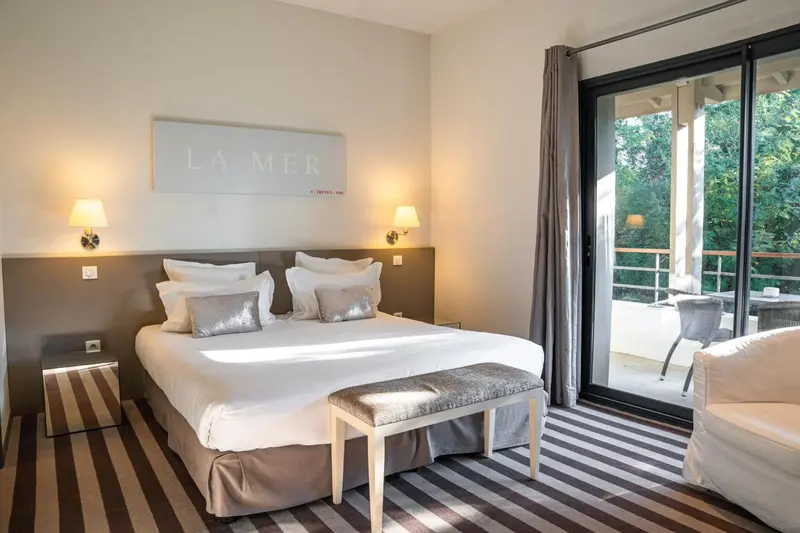 Une chambre lumineuse avec un grand lit et un accès à une terrasse.