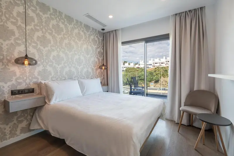 Chambre lumineuse avec un grand lit et une vue sur la mer.