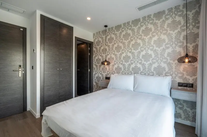 Une chambre avec un grand lit recouvert de draps blancs et des lampes suspendues.