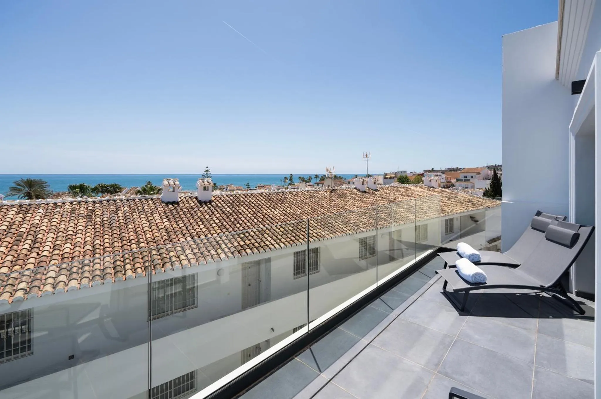 Terrasse avec transats et vue sur la mer et les toits.
