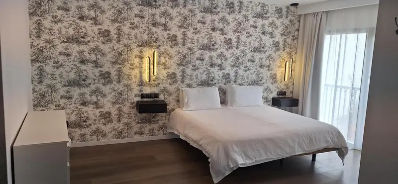 Une chambre moderne avec un lit double et un mur décoré d'un motif tropical.