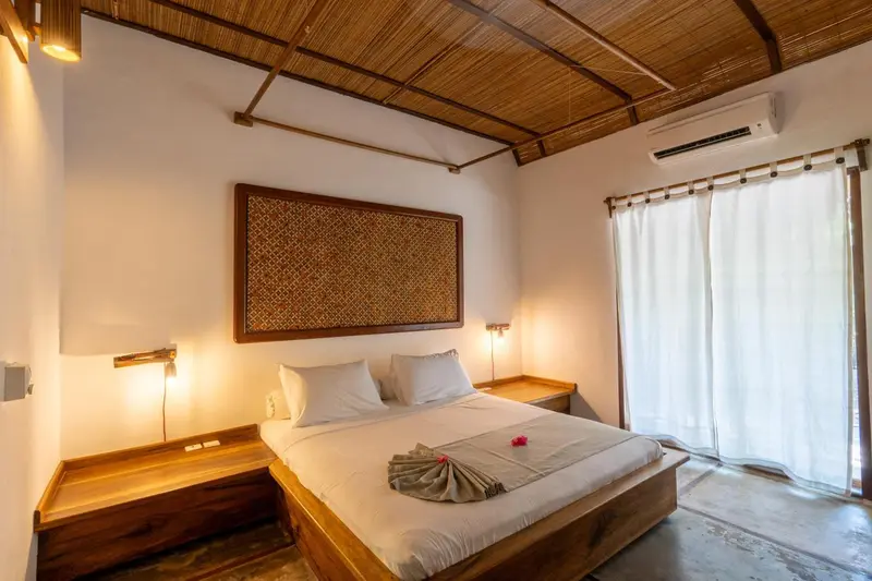 Une chambre lumineuse avec un lit double et une décoration murale en fibres naturelles.