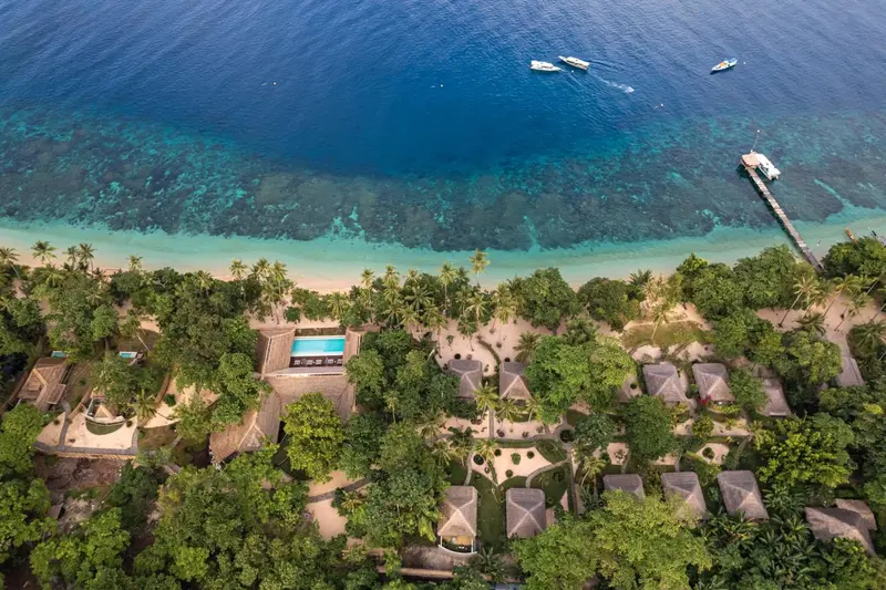 Vue aérienne d'une île tropicale avec des bâtiments et une plage.