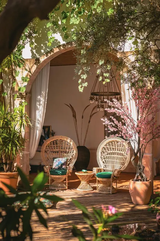 Espace de détente extérieur avec mobilier en rotin et végétation luxuriante.
