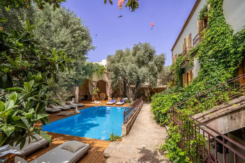 Une piscine turquoise entourée de chaises longues dans un jardin luxuriant.