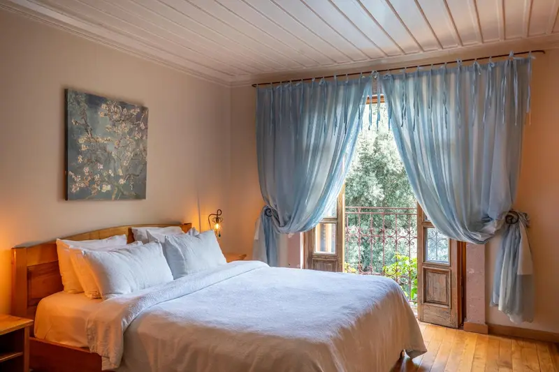 Une chambre lumineuse avec un grand lit et une fenêtre donnant sur la verdure.