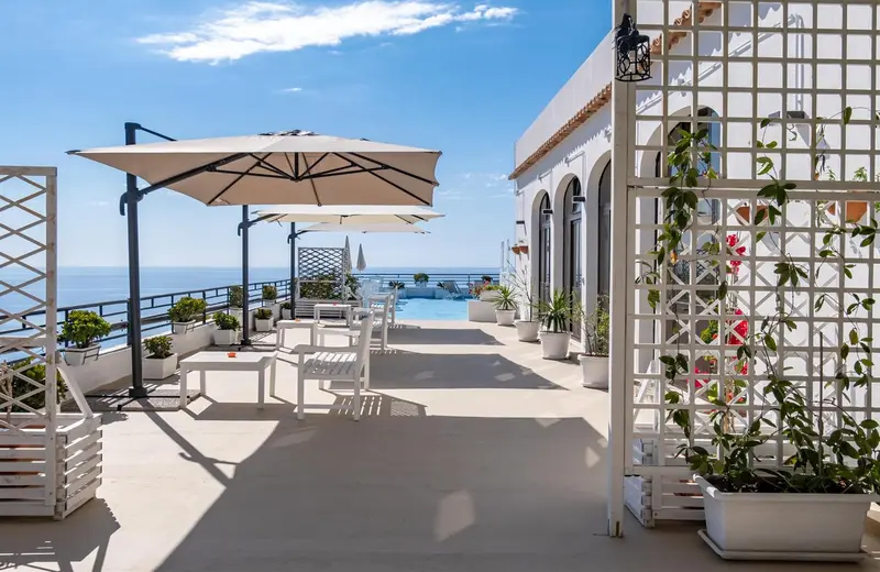 Terrasse aménagée avec mobilier blanc et vue sur la mer.