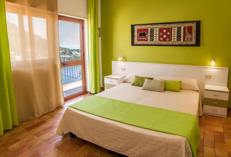 Une chambre lumineuse avec un lit double et un balcon.