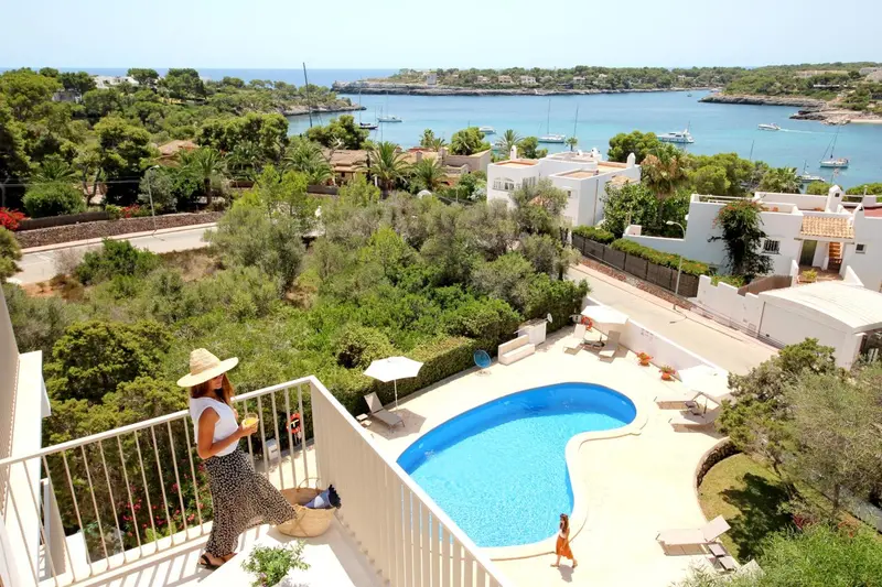 Une femme observe la vue depuis une terrasse avec piscine et végétation luxuriante.