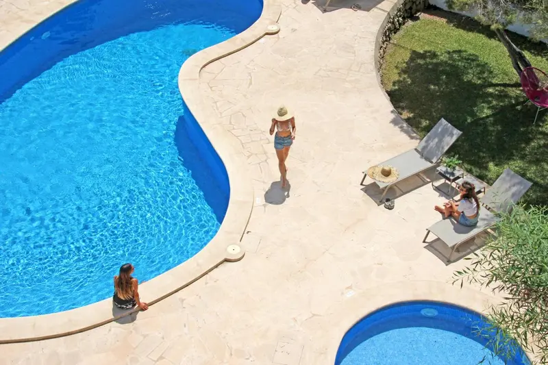 Vue aérienne d'une piscine avec des personnes se relaxant au soleil.