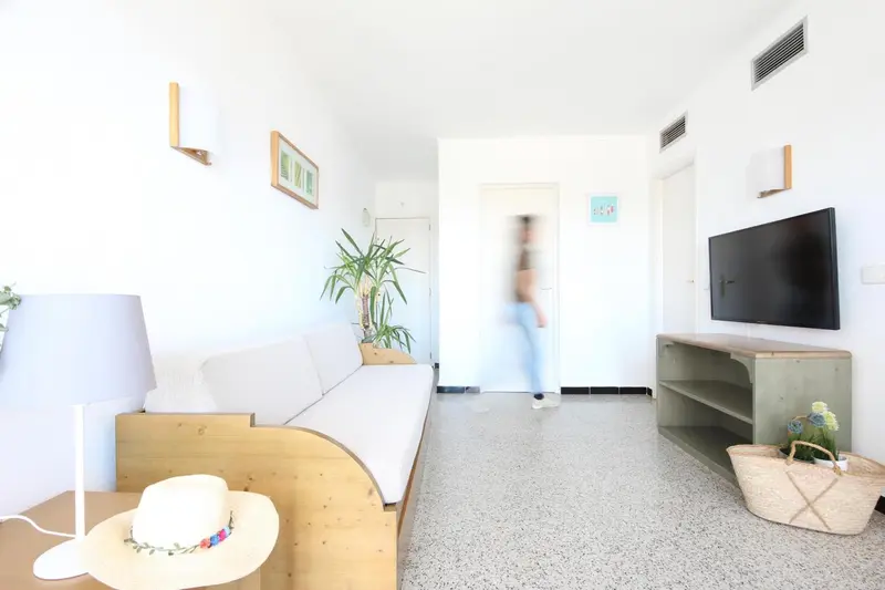 Espace de vie lumineux avec canapé et télévision.