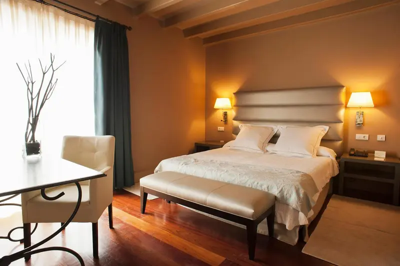Une chambre lumineuse avec un grand lit et un coin salon près de la fenêtre.