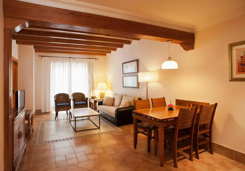 Espace de vie lumineux avec canapés, table basse et coin repas en bois.
