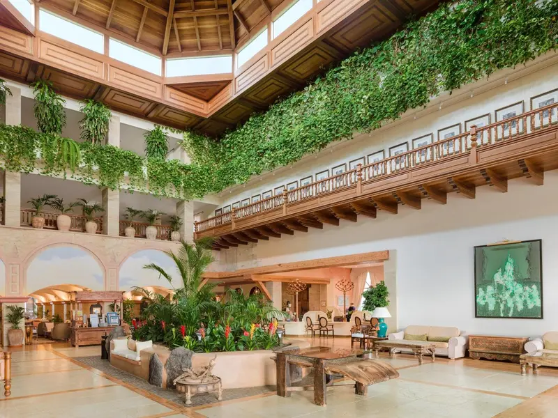 Vaste hall d'accueil avec plantes tropicales et mobilier clair.