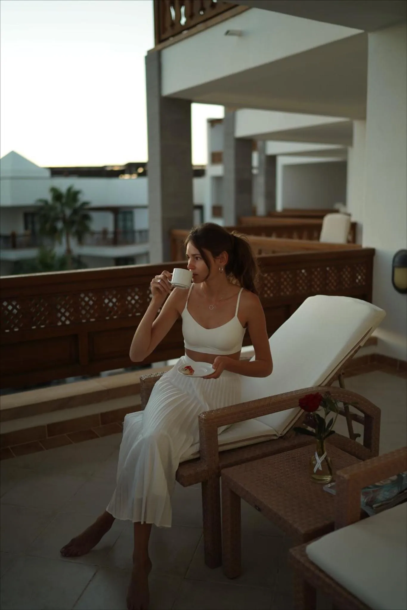 Une femme se détend sur une terrasse avec une boisson.
