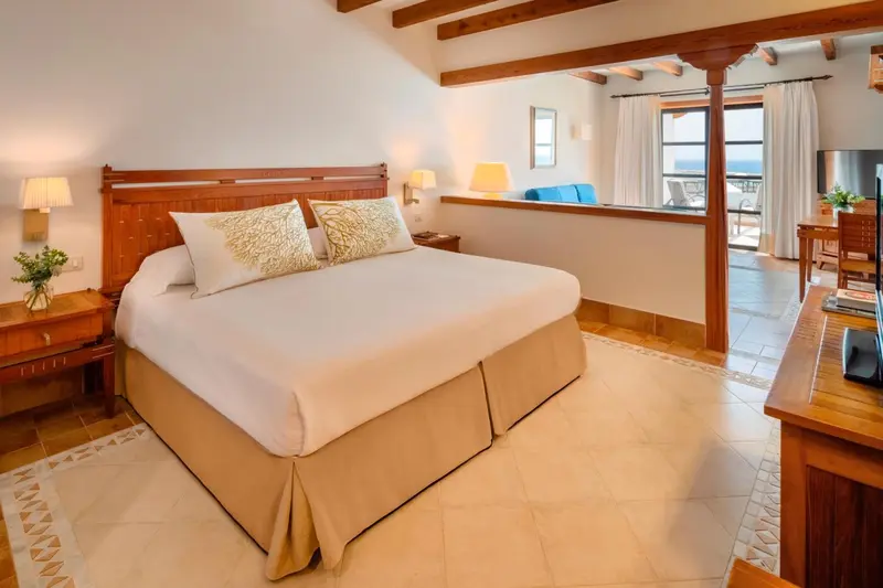 Une chambre lumineuse avec un grand lit et un coin salon.