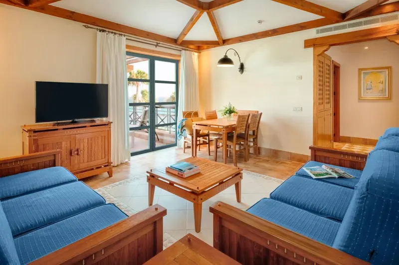 Espace de vie lumineux avec canapés bleus et table à manger en bois.