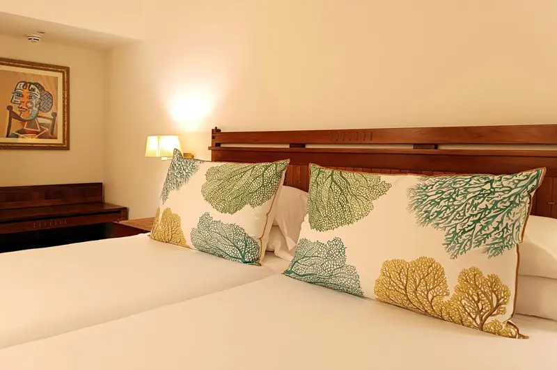 Lit double avec oreillers décorés dans une chambre lumineuse.